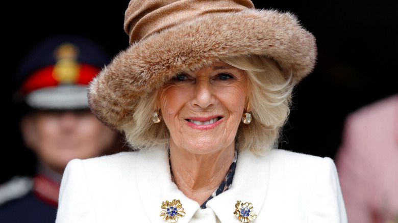 Queen Camilla smiles in a fur hat and diamond earrings