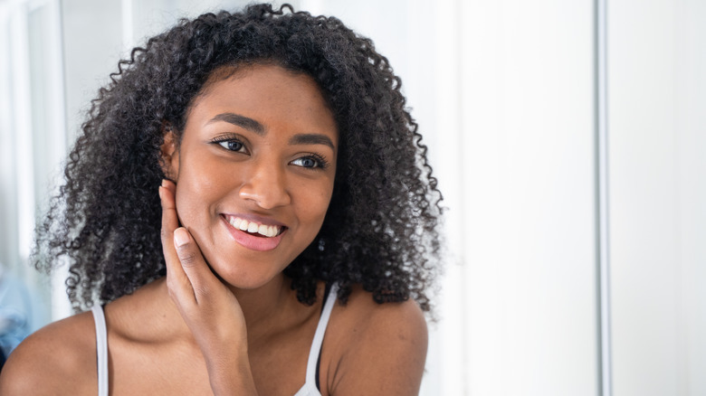 Black woman checking out her skin in the mirror