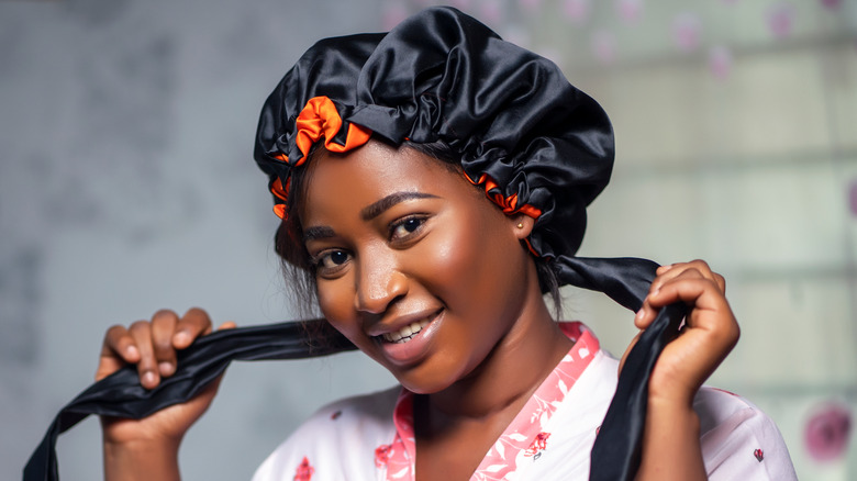 Woman wrapping hair in silk bonnet