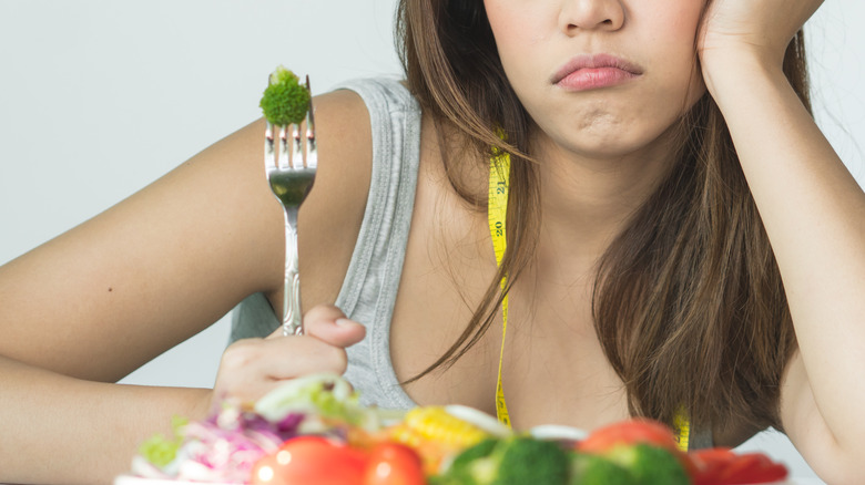 unhappy woman holding broccoli