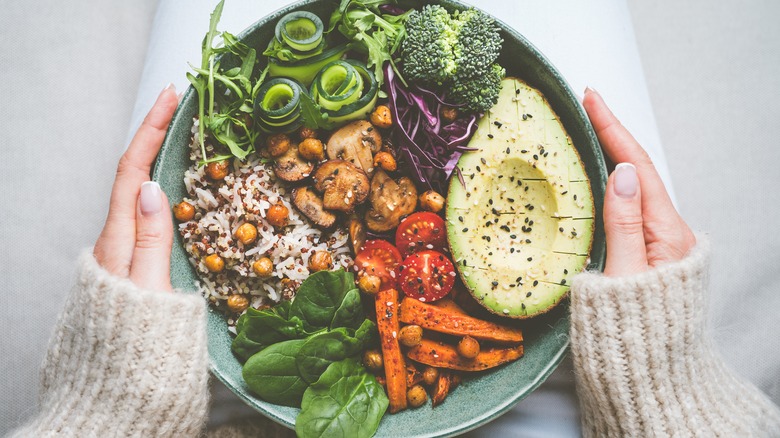 hands holding plate of vegetables