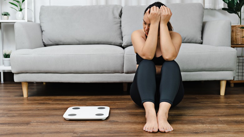 woman upset sitting next to her scale