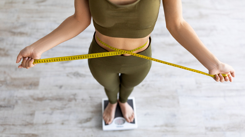 woman standing on a scale with a measuring tape