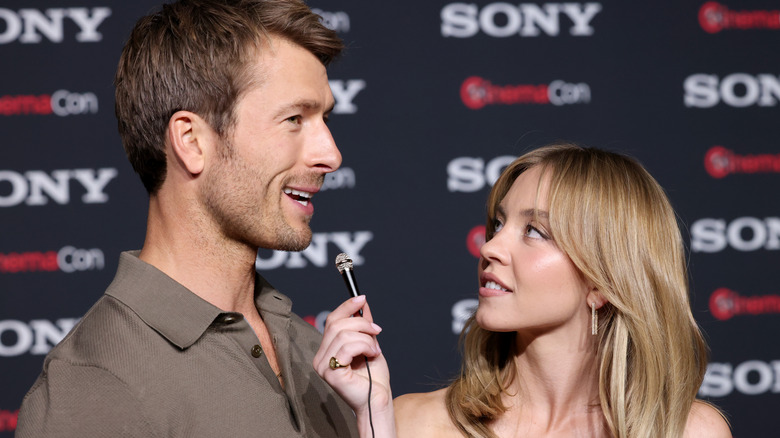 Sydney Sweeney holding a microphone for Glen Powell