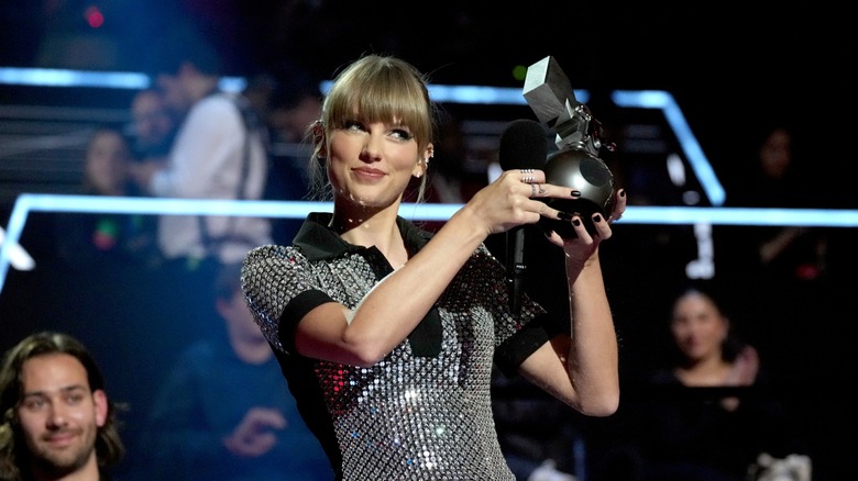 Taylor Swift smiling and holding up EMA