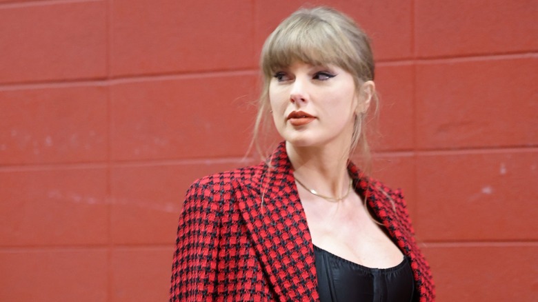 Taylor Swift looking over shoulder, wearing red and black jacket