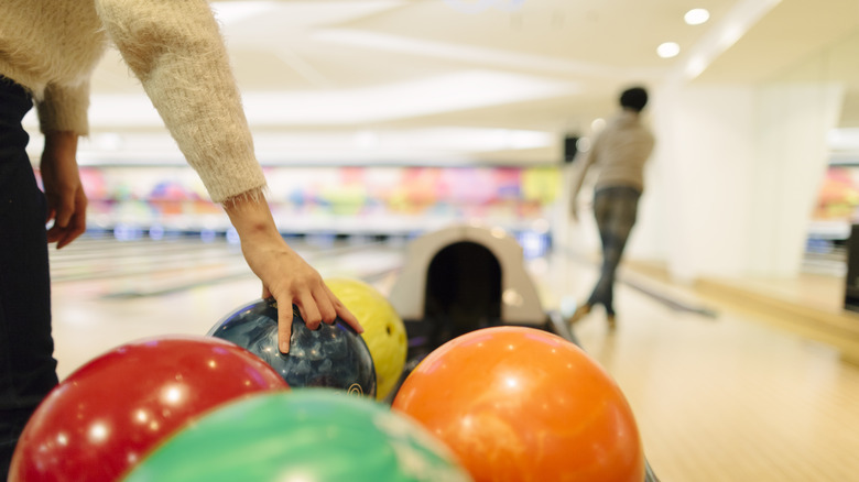 person grabbing bowling ball