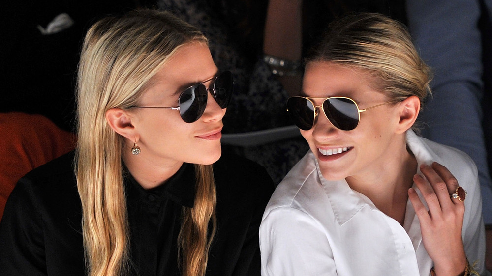 The Olsen twins watch a fashion show together in sunglasses