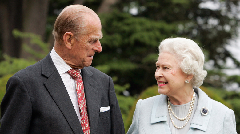 Queen Elizabeth and Prince Philip looking at each other smiling 