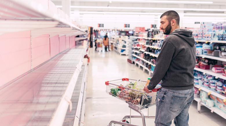 man shopping in store with empty shelves