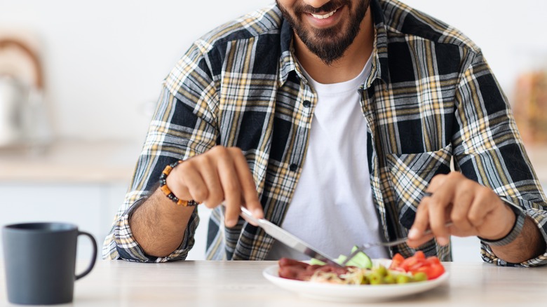 Man eating breakfast with utensils