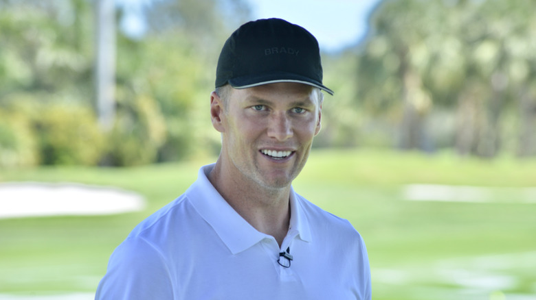 Tom Brady smiling wearing a black ballcap