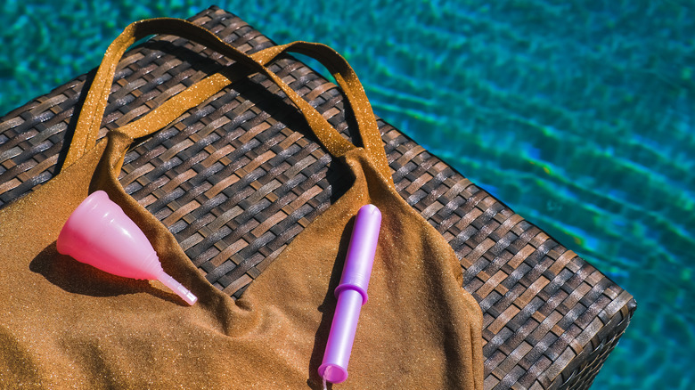 A tampon and menstrual cup placed on top of a swimsuit