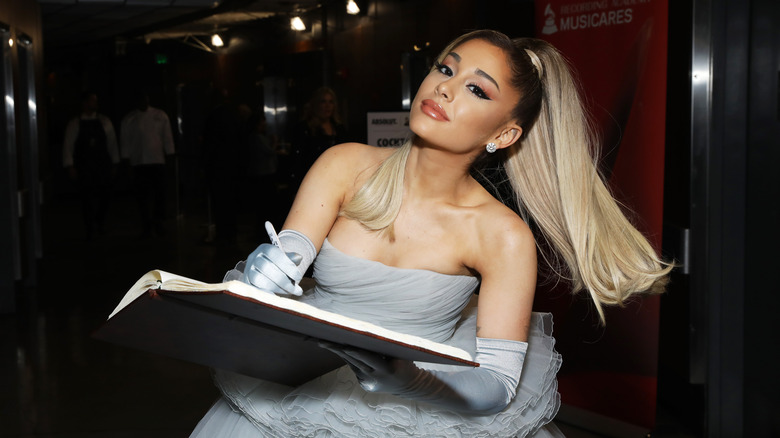 Ariana Grande writing in a book at the Grammys