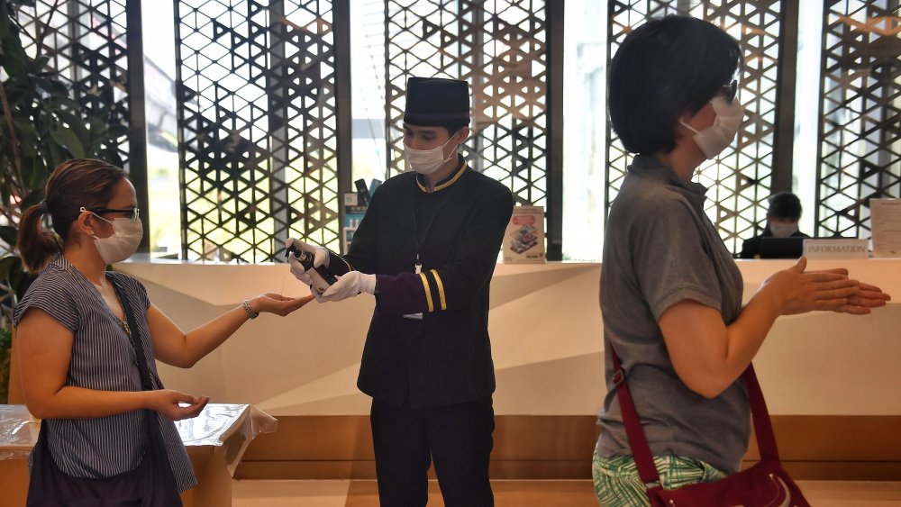 Hotel bellboy spraying hand sanitizer