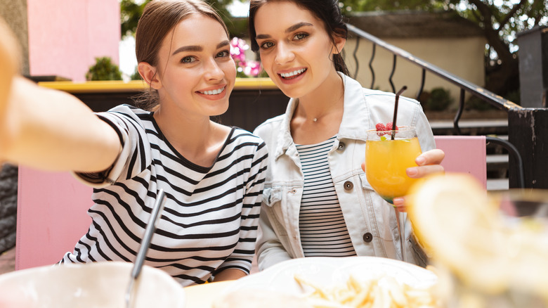 two women smiling while one takes a selfie