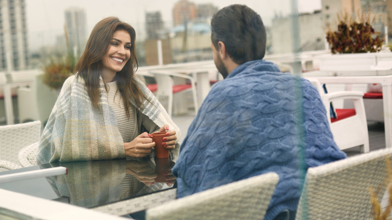 woman smiling at man while holding mug