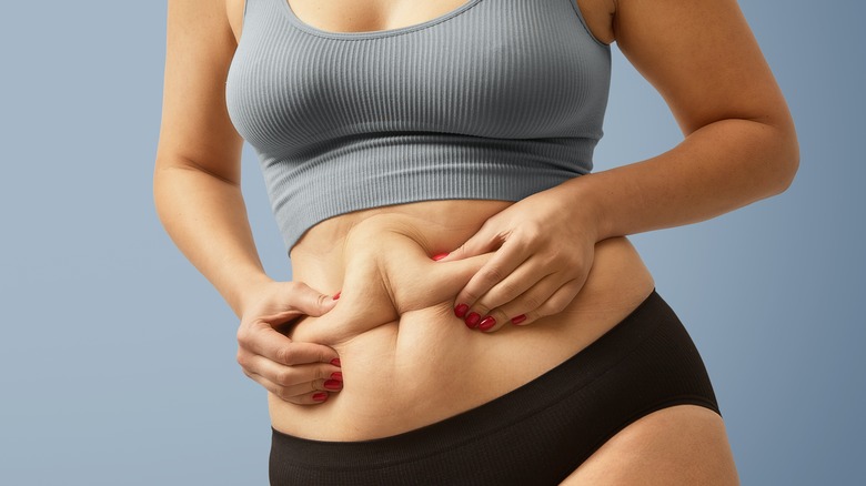 woman squeezing belly fat