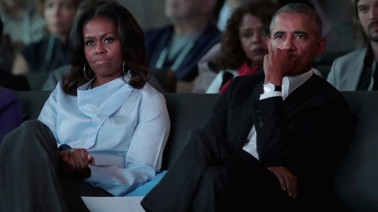 Michelle and Barack Obama listening to a speaker