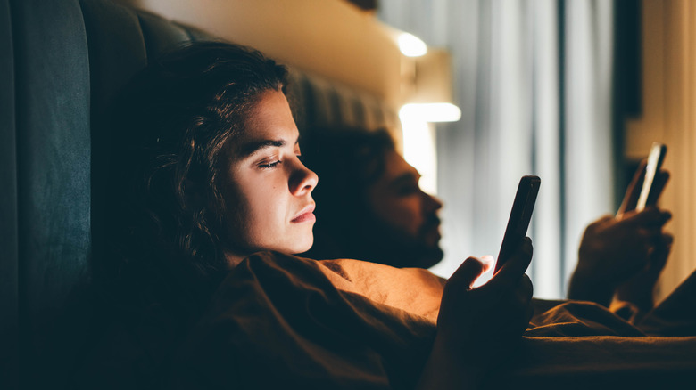 couple avoiding conversation, sitting on phones