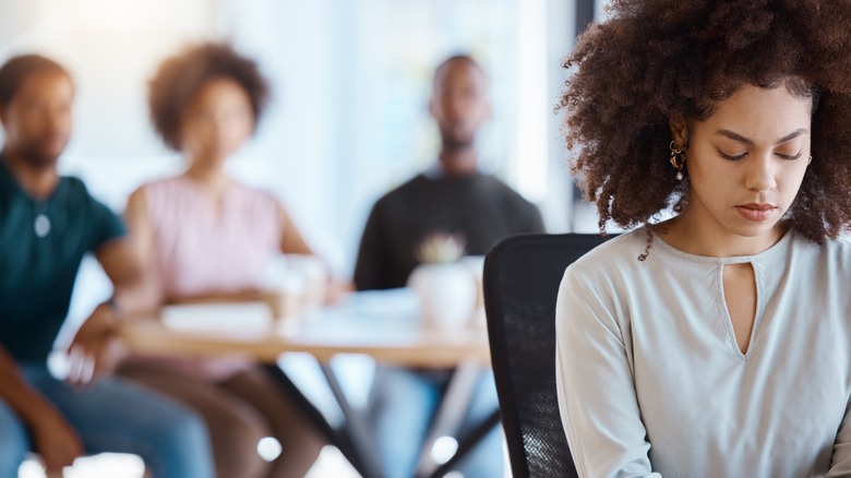 Woman sits apart from people