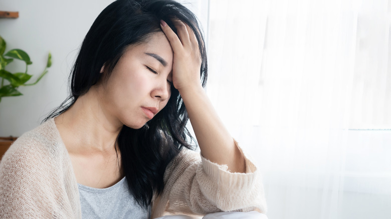 Tired-looking woman with hand on forehead