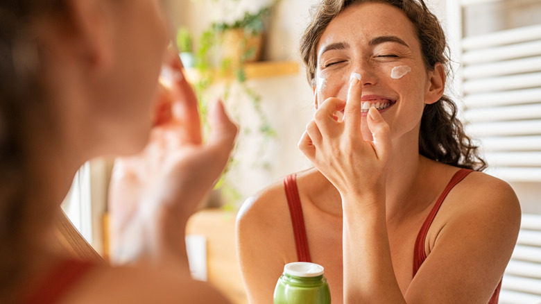 Smiling woman applying moisturizer