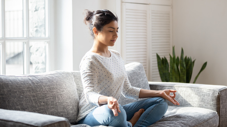 Woman meditates on the couch