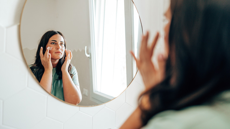 Woman applying tinted moisturizer 