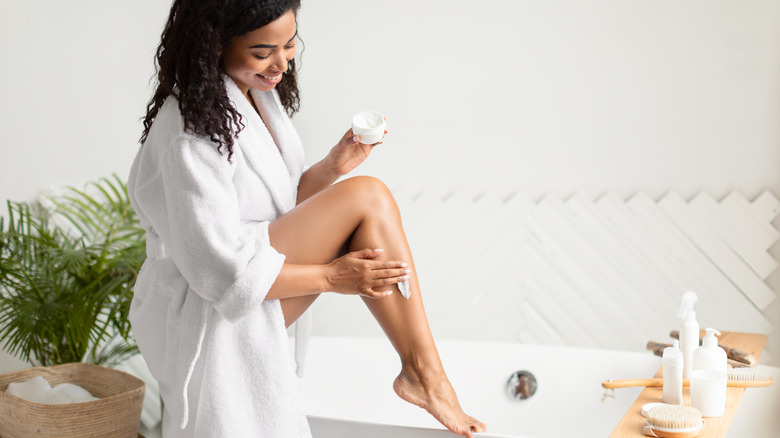 Woman applying moisturizer to legs