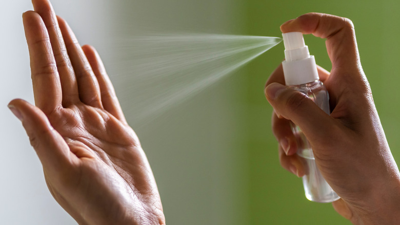 Woman spraying hand sanitizer on herself