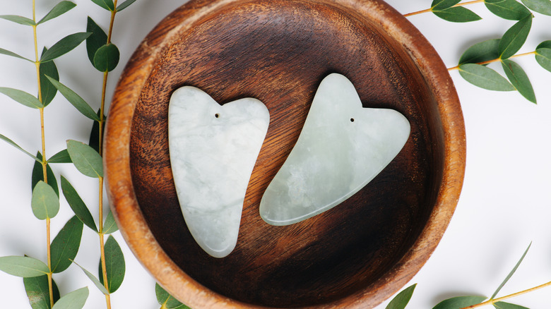 Two gua sha stones in a wooden bowl 