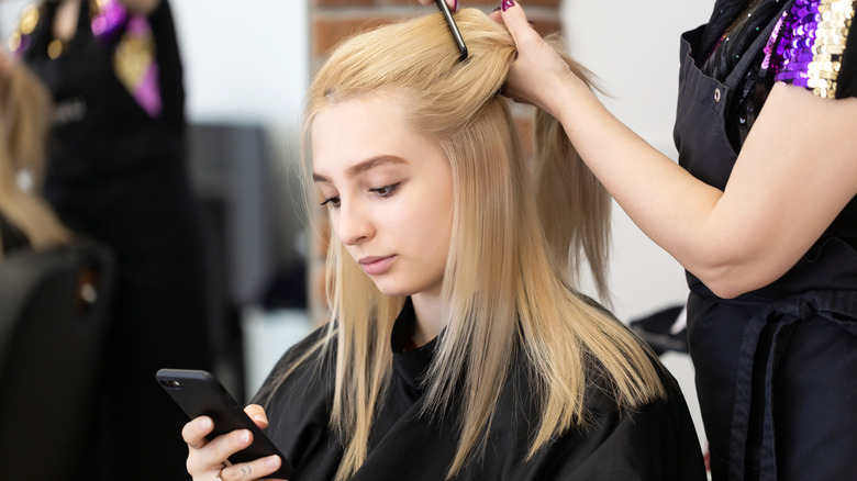 Woman staring at her phone during haircut