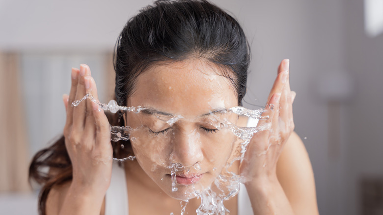 Woman washing her face with water