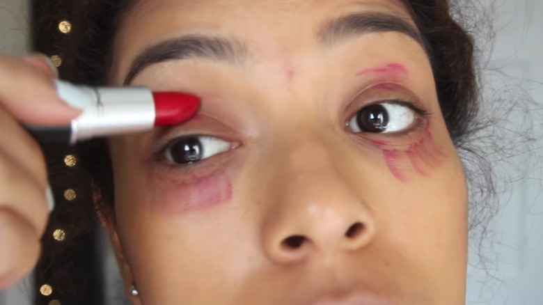 A woman using red lipstick as concealer