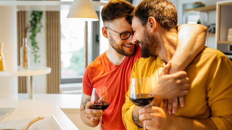 two smiling men drinking wine