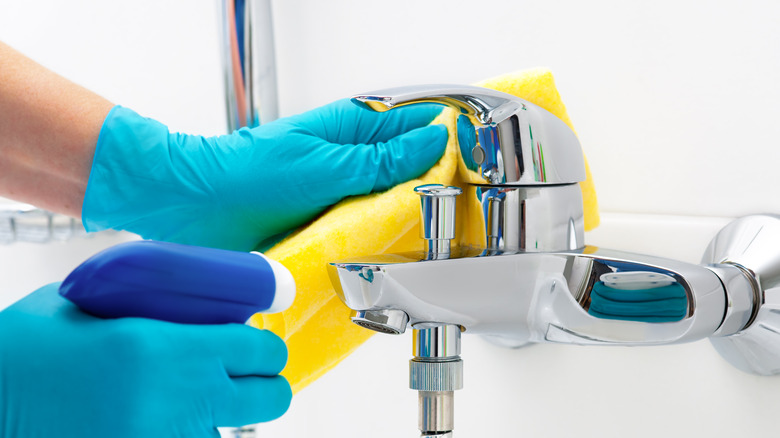 Person wearing rubber gloves cleaning a sink