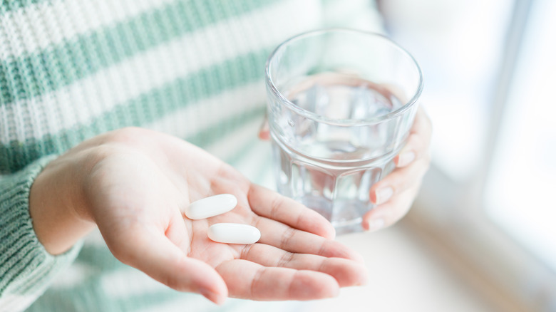 Hands with pills and water glass