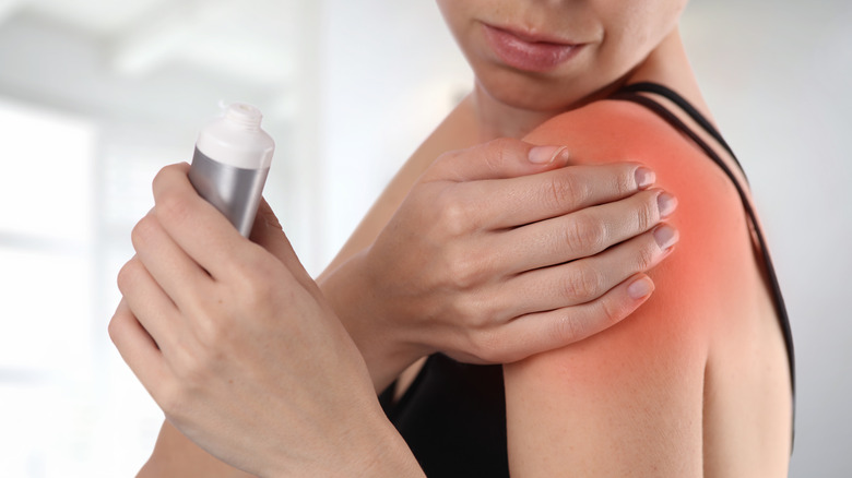 woman rubbing cream on shoulder