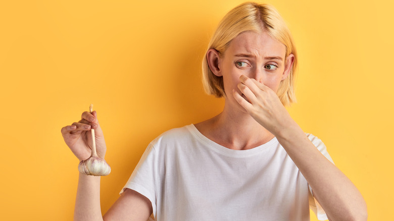 Woman holding garlic and pinching nose