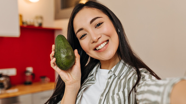 woman taking selfie with avocado