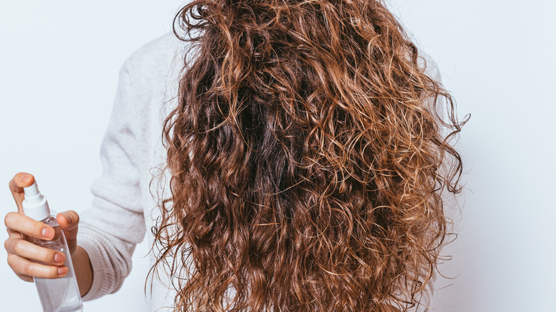 woman spraying oil on hair