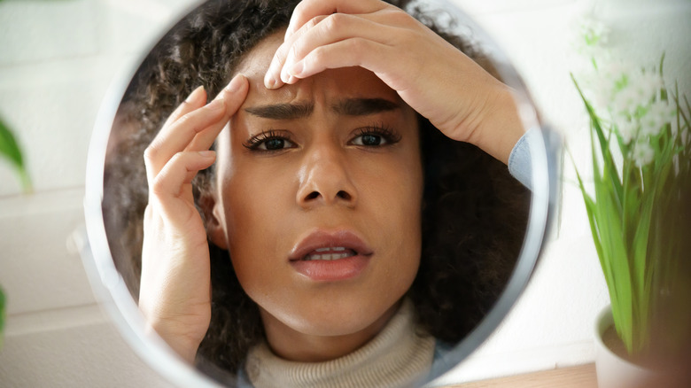 Woman squeezing her skin in the mirror