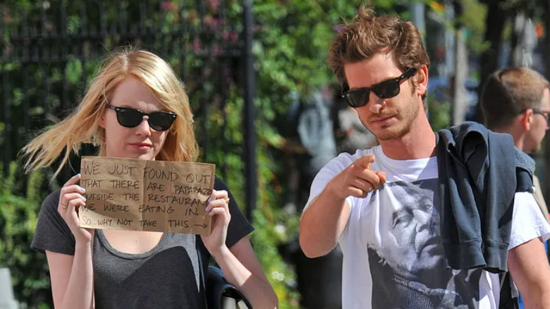 Emma Stone holding sign and Andrew Garfield pointing