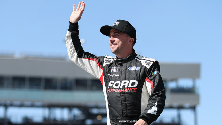 Frankie Muniz waving to unseen crowd in racecar driver outfit