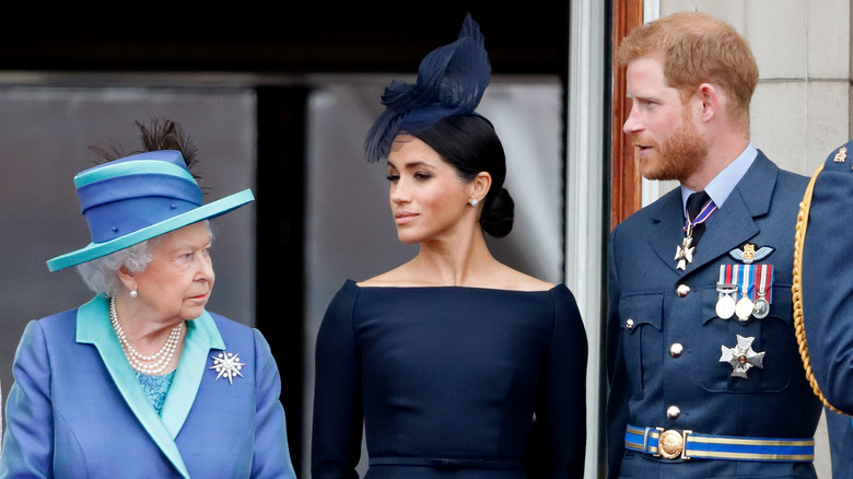 Queen Elizabeth, Meghan Markle, and Prince Harry standing on the balcony of Buckingham Palace