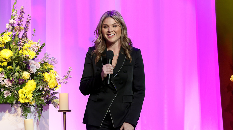 Jenna Bush Hager in a black suit holding a microphone