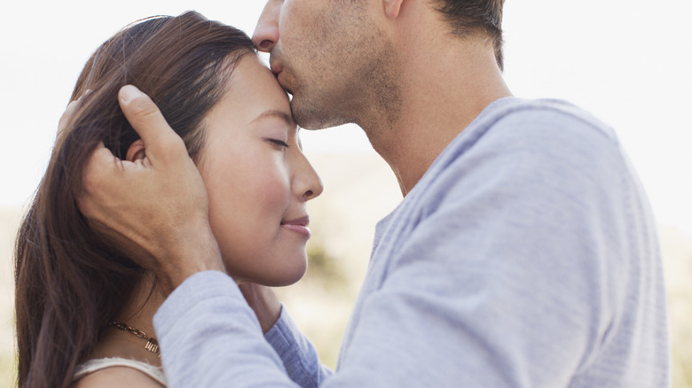 Man kissing woman on forehead