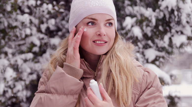 woman applying face cream in winter