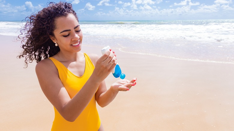 woman on beach applying sunscreen